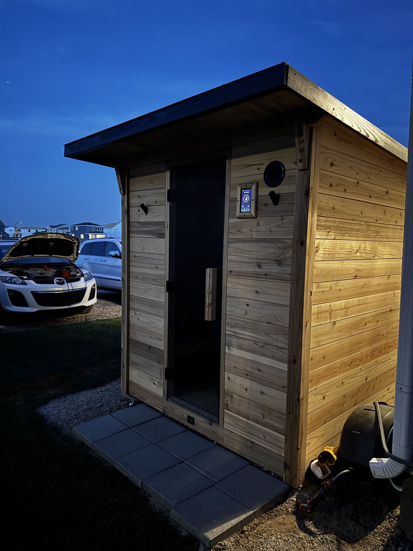 The cedar sauna lit up at blue hour